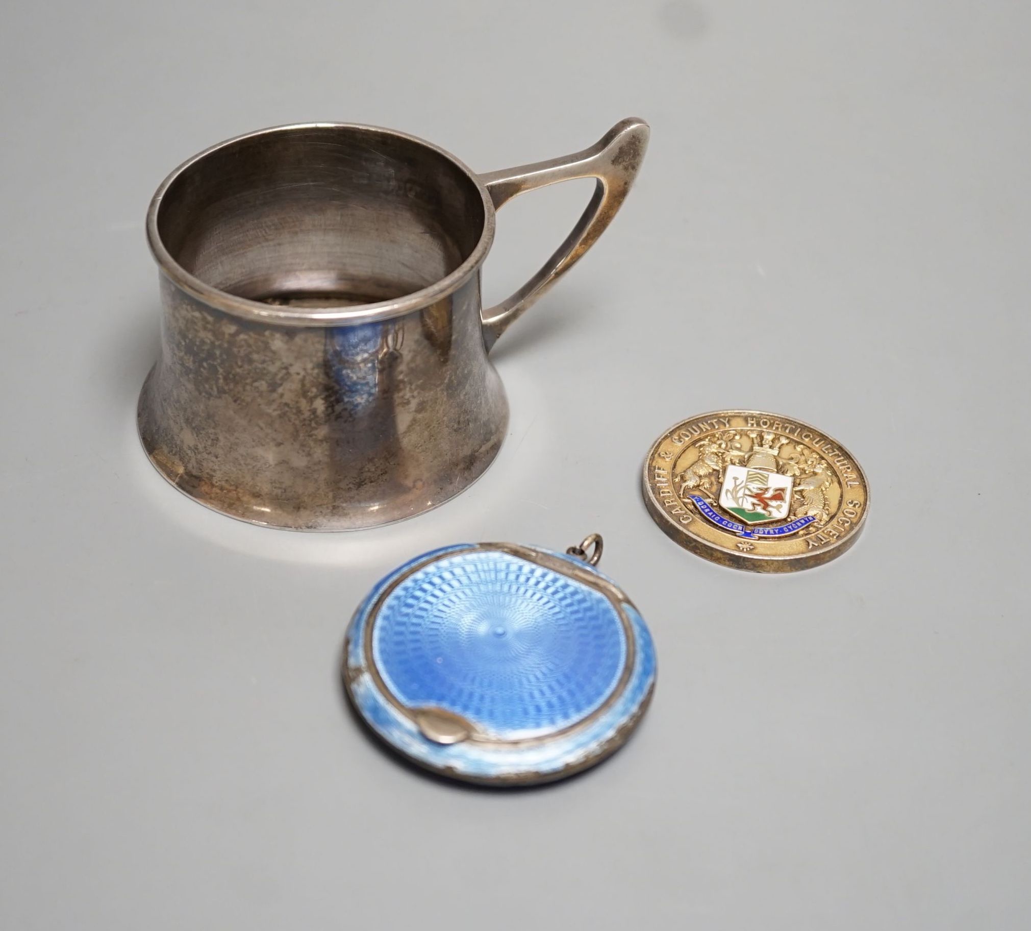 A George V silver cup holder, Birmingham, 1918, a silver and enamel Cardiff & County Horticultural Society medallion and a silver and enamel compact(a.f.)